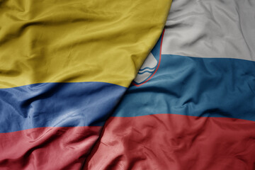 big waving national colorful flag of slovenia and national flag of colombia .