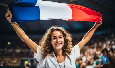 An excited female sports spectator holding a france flag in a sports stadium