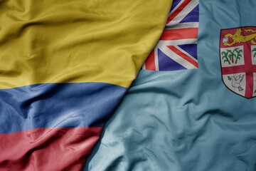 big waving national colorful flag of Fiji and national flag of colombia .