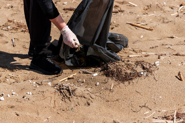 Close up view of volunteer collecting garbage on the beach. Environment concept.