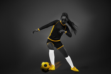 Fototapeta na wymiar Young woman, soccer playing in motion during game, dribbling ball over dark background. Yellow elements. Monochrome. Concept of competition, tournament, match, game. Creative design.