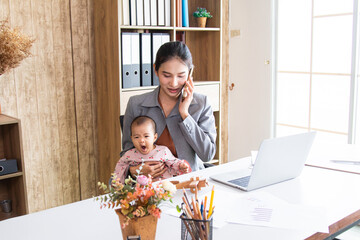 Asian parent working while looking after a young baby or toddler, single mother businesswoman...