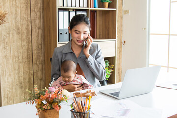 Asian parent working while looking after a young baby or toddler, single mother businesswoman...