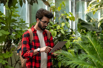 Young guy in checkered shirt in a botanical garden