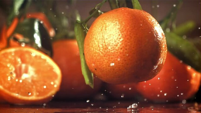 A whole tangerine falls on a wet board. Filmed on a high-speed camera at 1000 fps. High quality FullHD footage