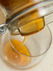 Liquid honey poured into a glass. A natural source of simple sugars and valuable micronutrients.