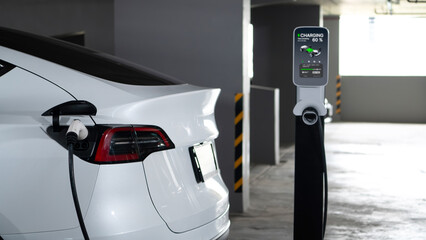 EV electric car recharge at shopping center parking lot charging in downtown city showing urban...