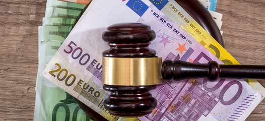 financial judgment with wooden judge's hammer and stack of eu euro banknotes