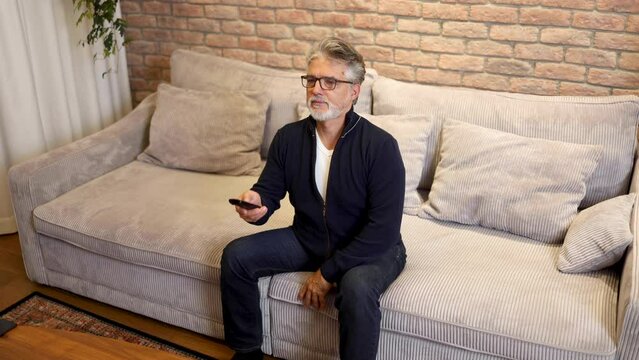 Mature man watching TV - Powered by Adobe