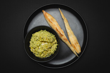 Avocado and lemon juice salad with crispy baguette on a black background.