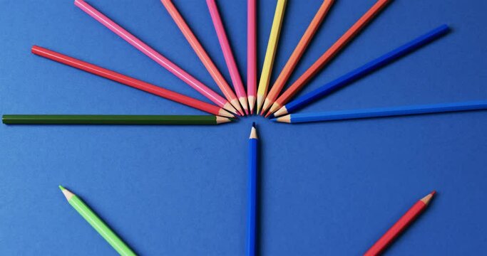 Close up of crayons arranged on blue background, in slow motion