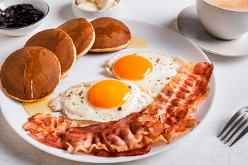 Breakfast with fried eggs, bacon and pancakes