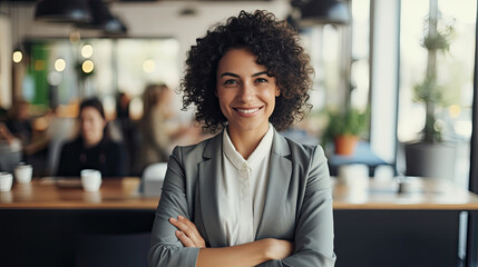 A smart and smiling beautiful confident business woman smiles at the camera with crossed arms and formal wear against a modern office background created with Generative AI Technology - obrazy, fototapety, plakaty