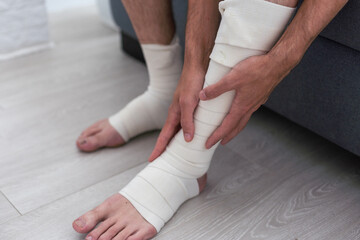 Man bandaging injured ankle. Injury leg. First aid for sprained ligament or tendon