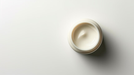 Facial moisturizer in open glass jar  on white background. Skin care concept. Top view, space for text.