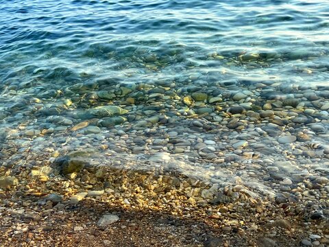 Sea clear water pebbles gravel stones at the bottom. 