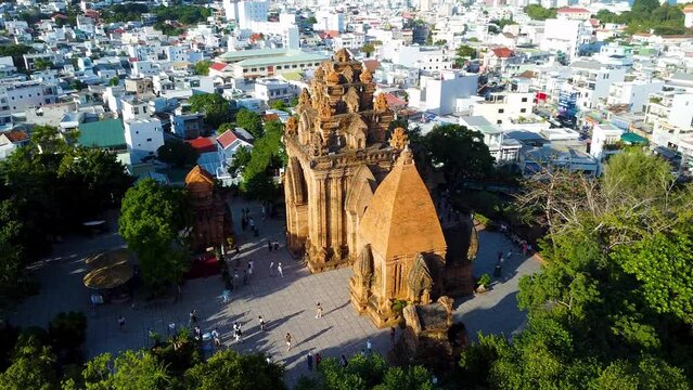 Aerial approach Po Nagar Cham temple red tower Vietnam Nha Trang sunny cityscape. Authentic culture Asia. Modern buildings city bridge active road traffic river fishing old boats. Religion buddhism