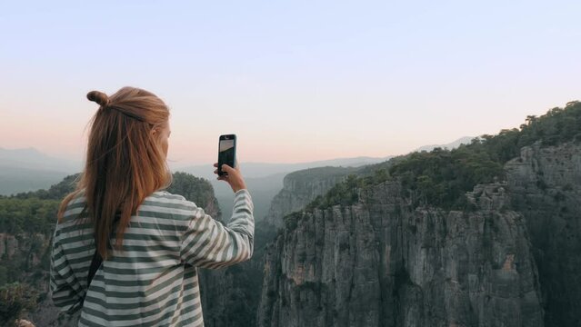 Travel woman use smartphone shooting photo video panorama of mountain canyon at sunset sunrise
