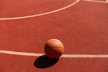 Basketball on Court Floor close up with blurred arena in background.