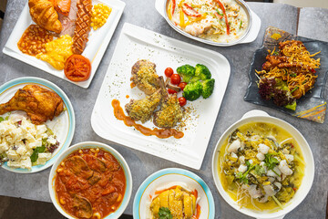 Top view of a set of different dishes like lamb and fish and breakfast on a table in a restaurant