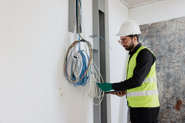 electrical engineers or technicians is professionally inspecting the wiring and systems in the building. Check electrical equipment to meet safety standards. Use a tablet to check buildings. - obrazy, fototapety, plakaty