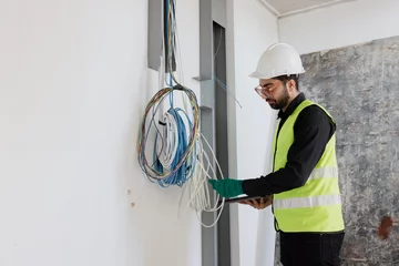 Fotobehang electrical engineers or technicians is professionally inspecting the wiring and systems in the building. Check electrical equipment to meet safety standards. Use a tablet to check buildings. © Rapeepat
