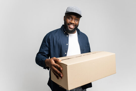 An approachable young African-American man delivers a package with a welcoming smile, creating a scene of friendly and efficient service