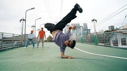 Low angle camera of hipster doing freeze pose while looking at camera. Group of break dancer...