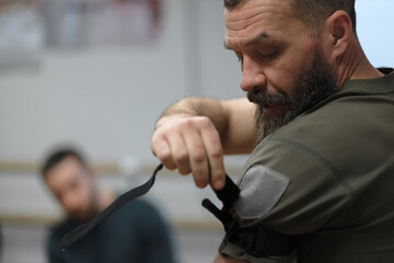 The instructor demonstrates the technique of applying a tourniquet