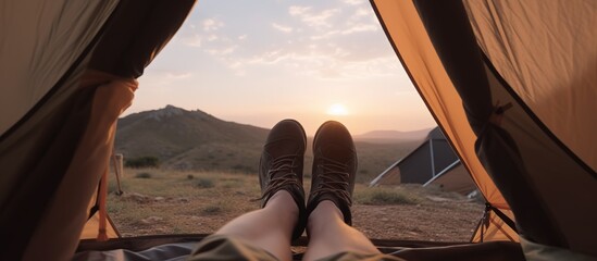 Closeup photo of feet in tent, sunset camping in the mountains