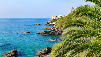 Nervi. Genoa, Italy. View of the sea from the coast of Nervi, near Genoa, on a warm and sunny October day. Gropallo Tower in the distance. Some people canoeing among the rocks. 2023-10-06. - obrazy, fototapety, plakaty