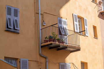 Gelbe mediterrane Hausfassade mit Balkon im Sonnenlicht, Korsika, Frankreich - obrazy, fototapety, plakaty