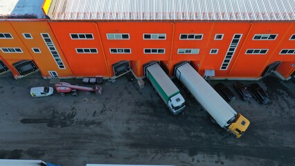 Unloading-loading of goods into trucks near a large logistics center, warehouse. Trucks loaded with goods. Aerial view of a commodity distribution center serving stores in a large metropolitan area.