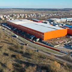 Complex of huge warehouses outside the city limits for storage of goods of retail chains in fall, winter in Europe. An aerial view of the orange and blue logistics center.