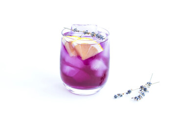 Lavender lemonade with ice and lemon in the drinking glass on the white background. Close-up.