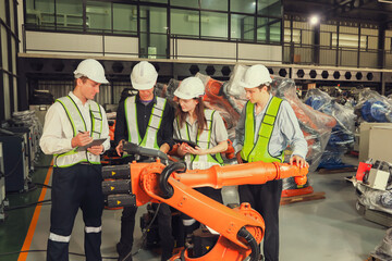 Team engineers robots electricians men and women brainstorming and consulting checking service new welding robots testing automatic electrical systems electronics in warehouse for Industry 4.0. 