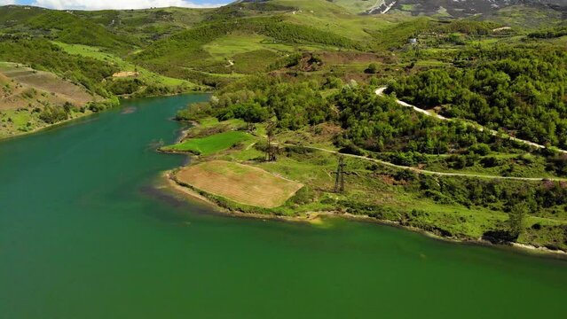 The drone runs along a lake and approaching a small encampment. About gold, oilfield, mining, gold mining, currency, stock market, Lake, sieve.