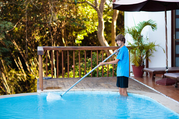 Boy cleaning swimming pool. Maintenance, service.