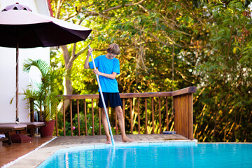 Boy cleaning swimming pool. Maintenance, service.