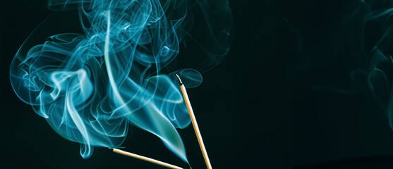 Räucherstäbchen mit blauem Rauch auf schwarzem Hintergrund, copy space