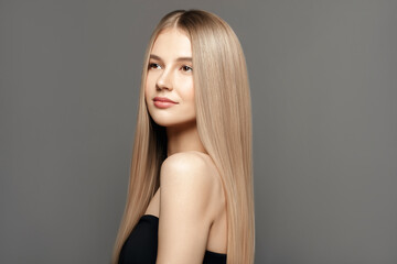 Hair care model.Beauty young woman with long healthy hair posing against grey background. Beauty salon concept