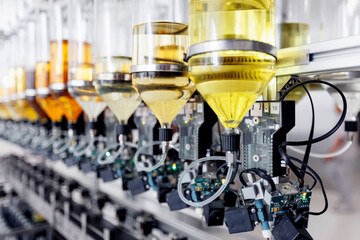 Automated nozzles filling clear perfume bottles with precision on factory line. Aroma water...