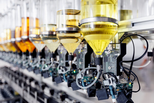 Automated nozzles filling clear perfume bottles with precision on factory line. Aroma water manufacturing process with conveyor