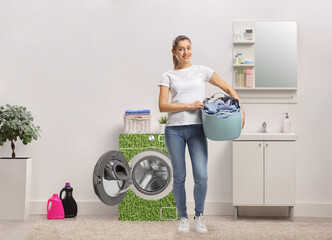 Woman in a bathroom with a power efficient washing machine holding a laundry basket