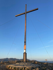 large summit cross marking the top of the mountain with a clear blue sky in the background