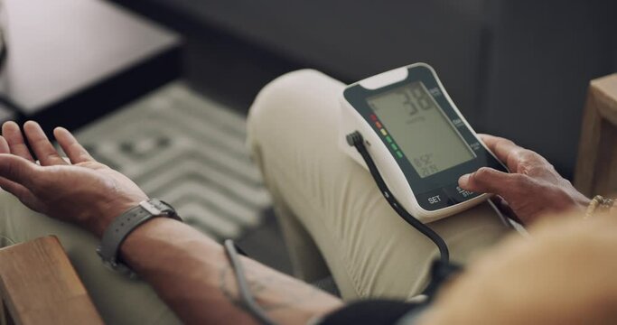 Arm, blood pressure and person on couch in home to monitor hypertension with a machine for healthcare. Medical, technology and equipment with adult in apartment for recovery, treatment or results