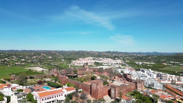 Gothic Silves Cathedral with Moorish Castle of Silves hills and blue sky in the background