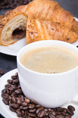 Breakfast consisting of fresh croissant with chocolate and coffee in white cup