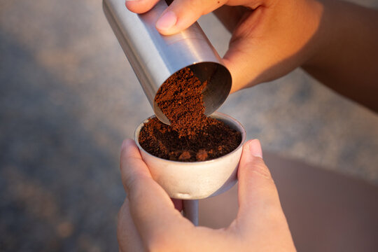 Aromatic roasted coffee beans fill a coffee powder container held in a hand, creating a close-up image capturing the essence of coffee