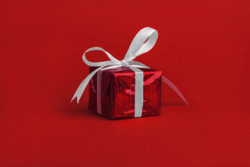 Gift box with white bow on red background. Concept of profit and benefit